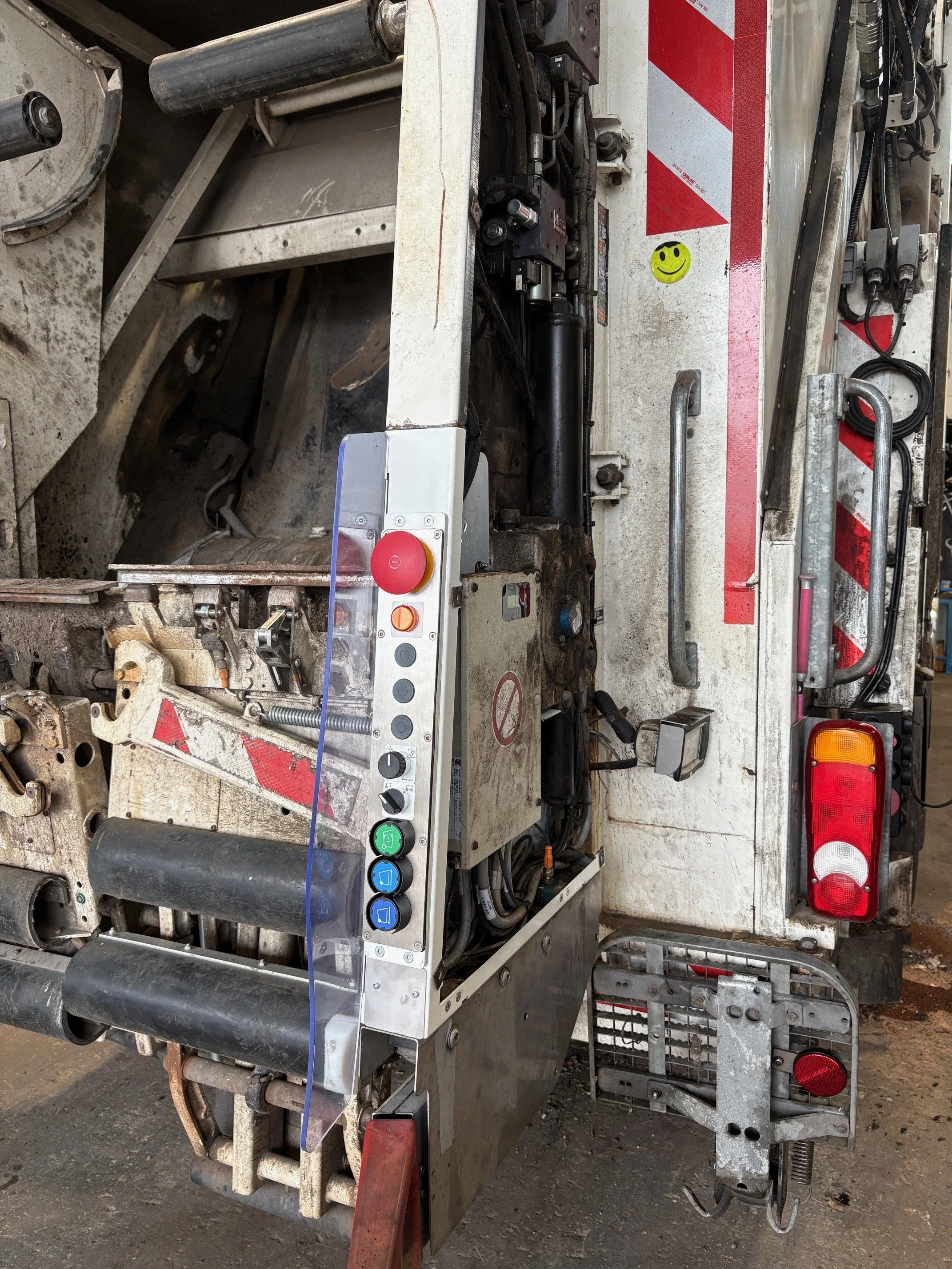 Nahaufnahme der Rückseite eines Feuerwehrwagens mit Kontrollpaneel, Warnbeleuchtung, Kabeln und Lüftungsschläuchen.