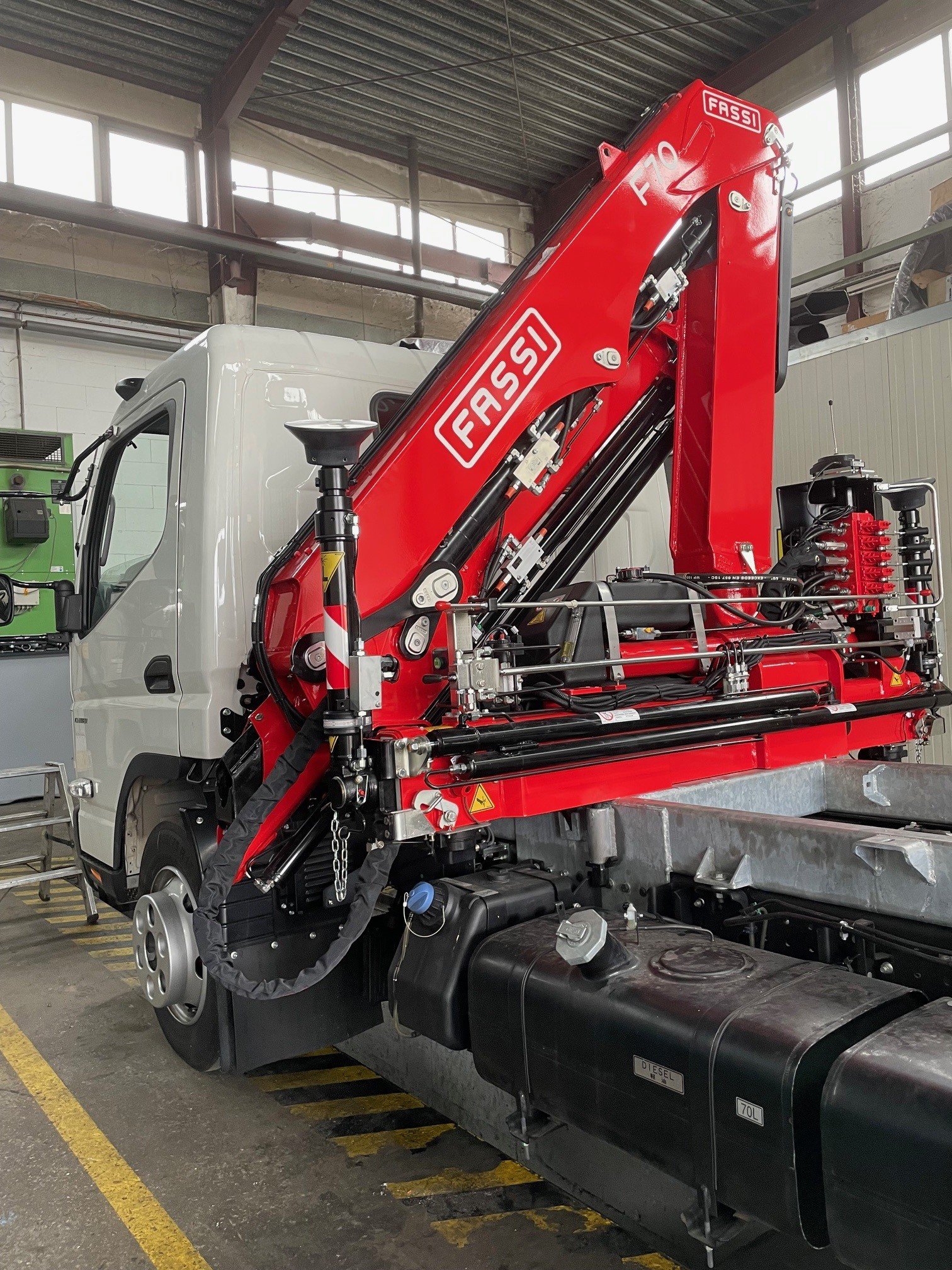 LKW mit rotem Kranarm, Fabrikhalle im Hintergrund, Kennzeichnung FASSI F10.