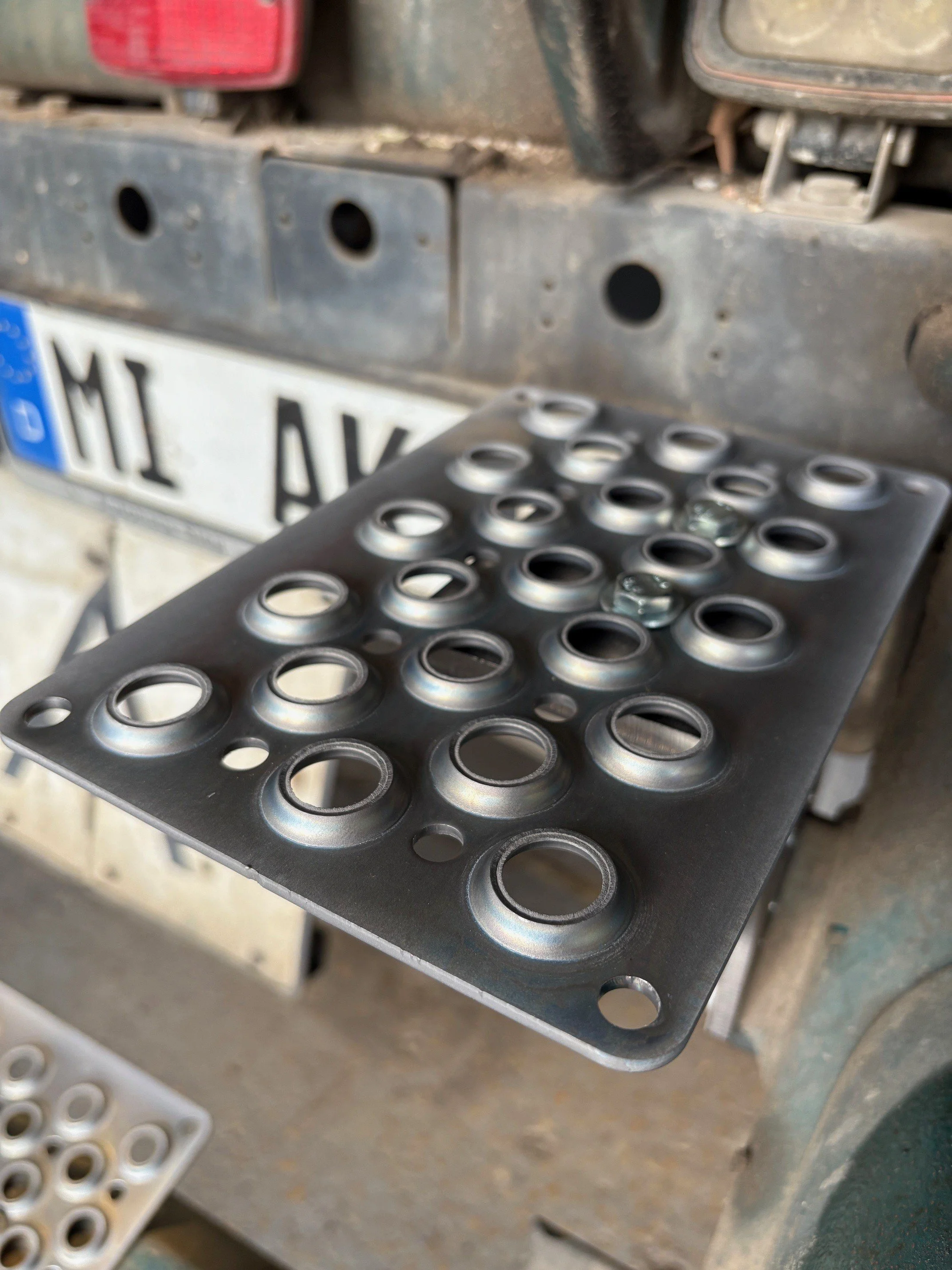 Metallplatte mit mehreren runden Bohrungen an dem Heck eines LKW.