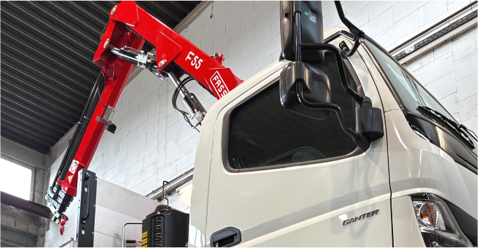 Baukran an einem weißen Lieferwagen in einer Lagerhalle.