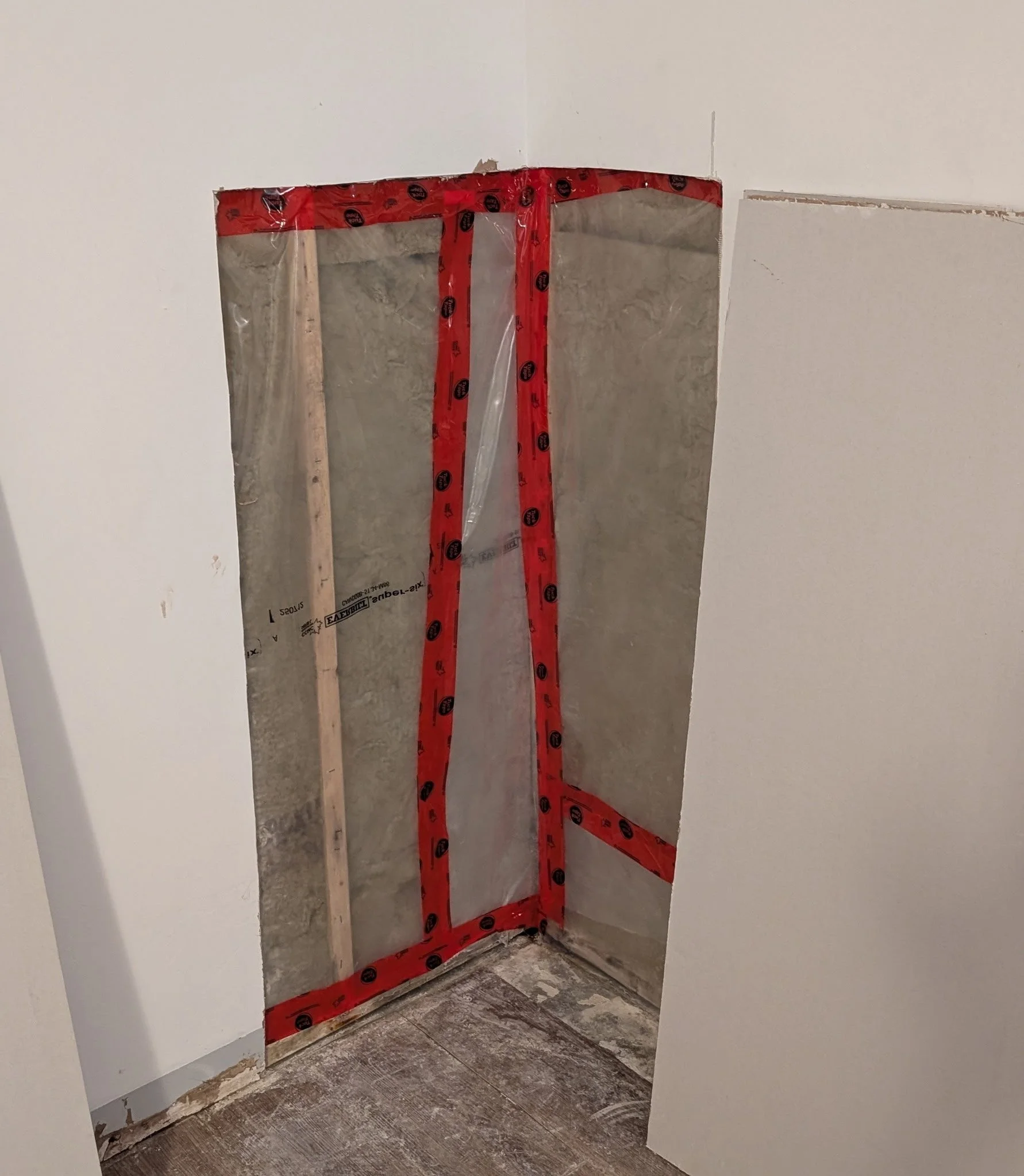 Open wall space with drywall and red tape around a rectangular cutout.