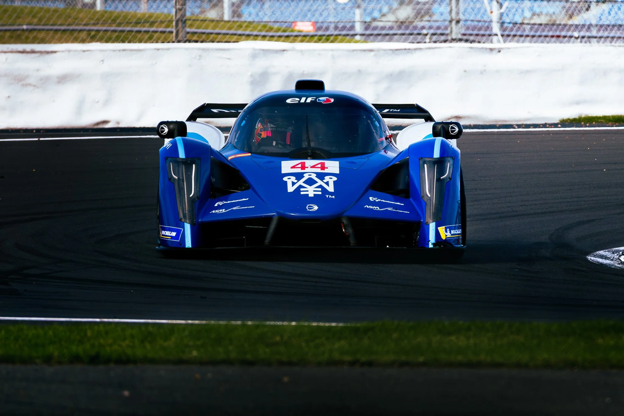 A blue race car with the number 44 on the front, driving on a racetrack.