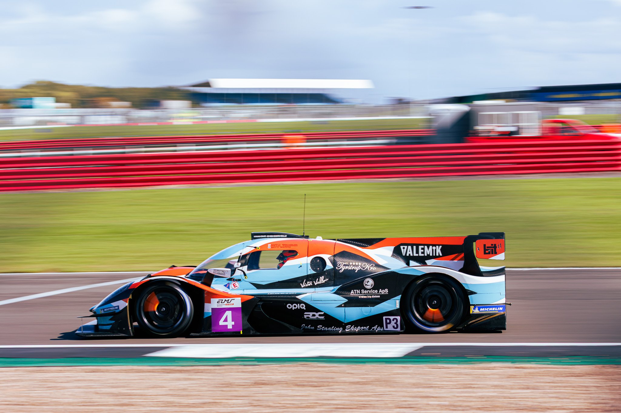 Race car on a track during daytime with a blurred background.