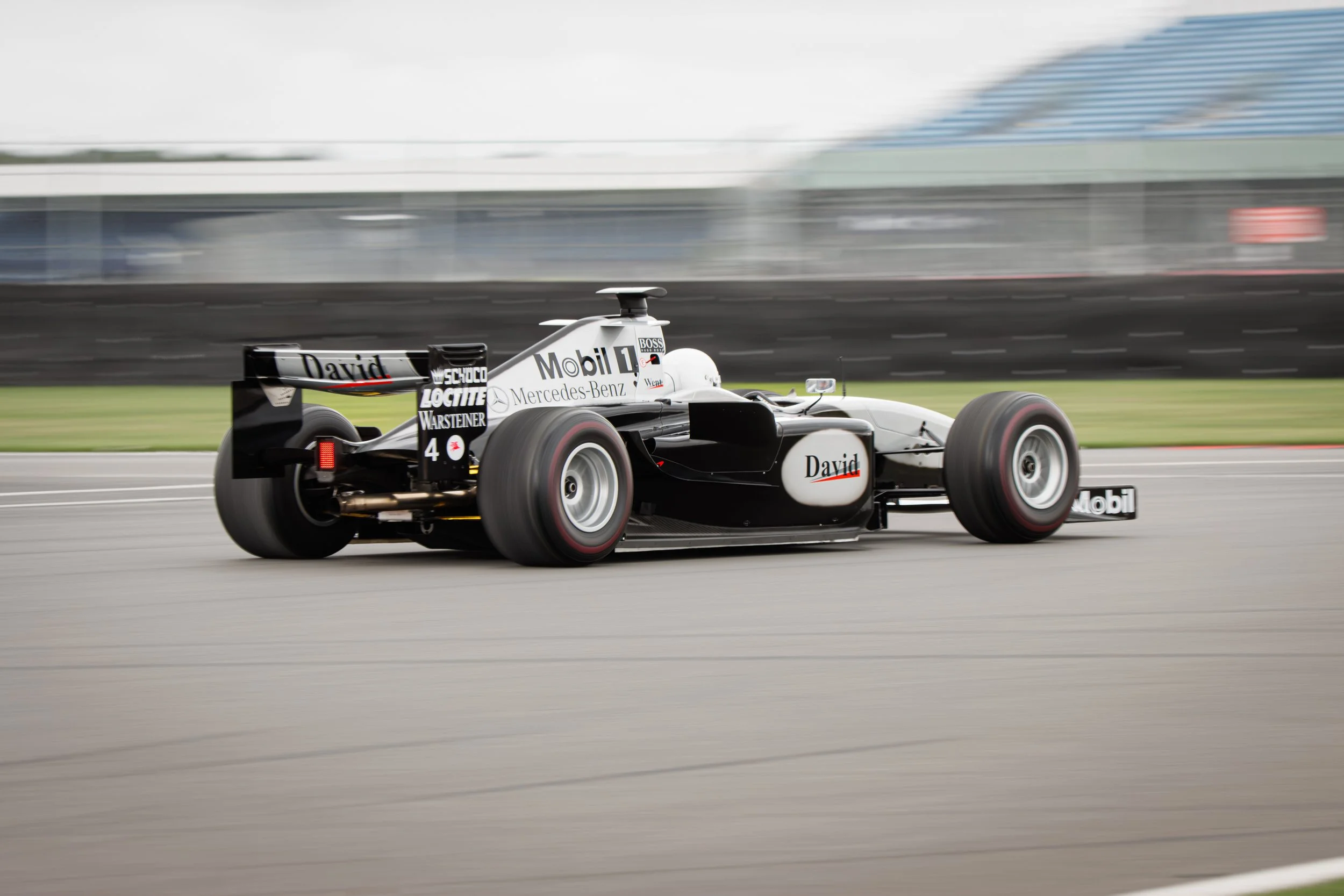 A classic black-and-white Formula 1 race car speeding on a race track during daytime.