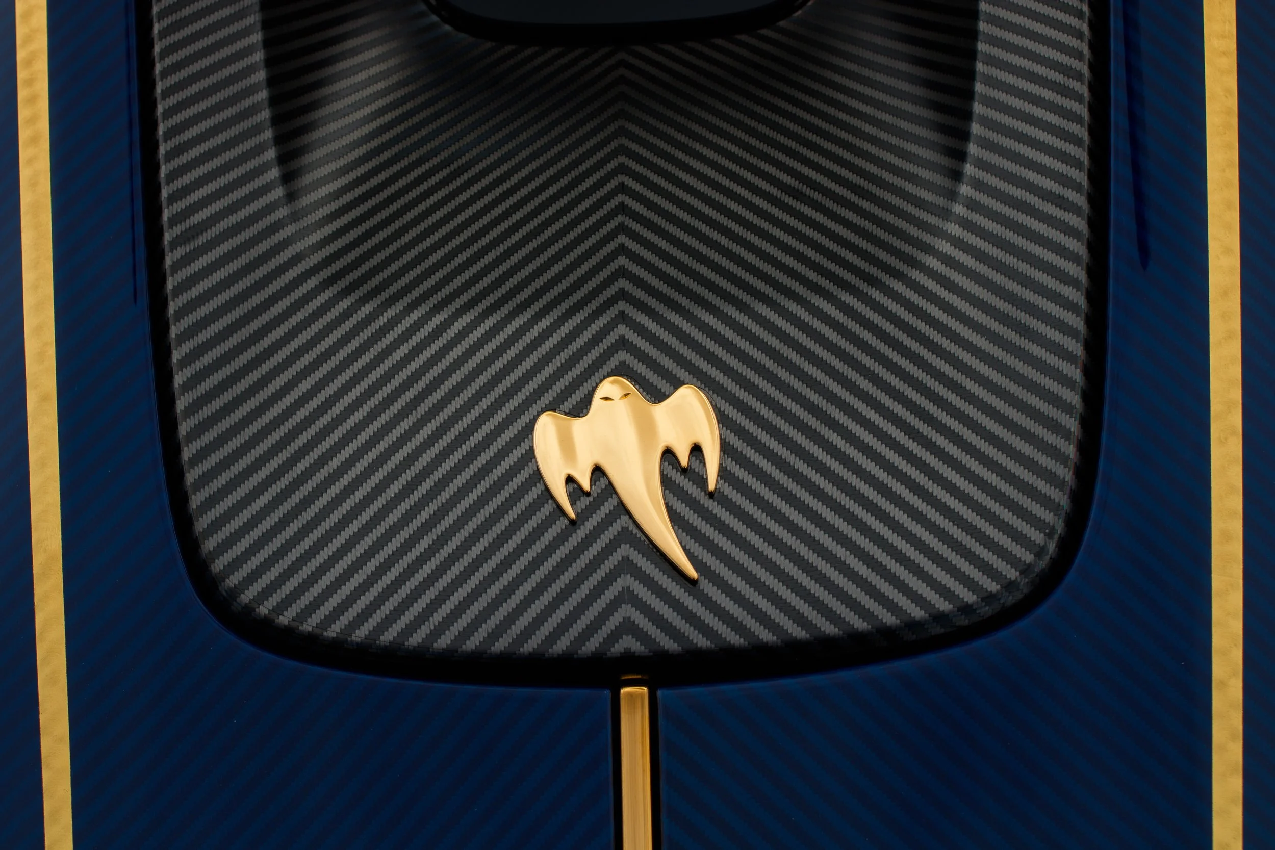 Close-up of a dark blue and black soccer jersey with gold accents, featuring a gold bat symbol in the center.