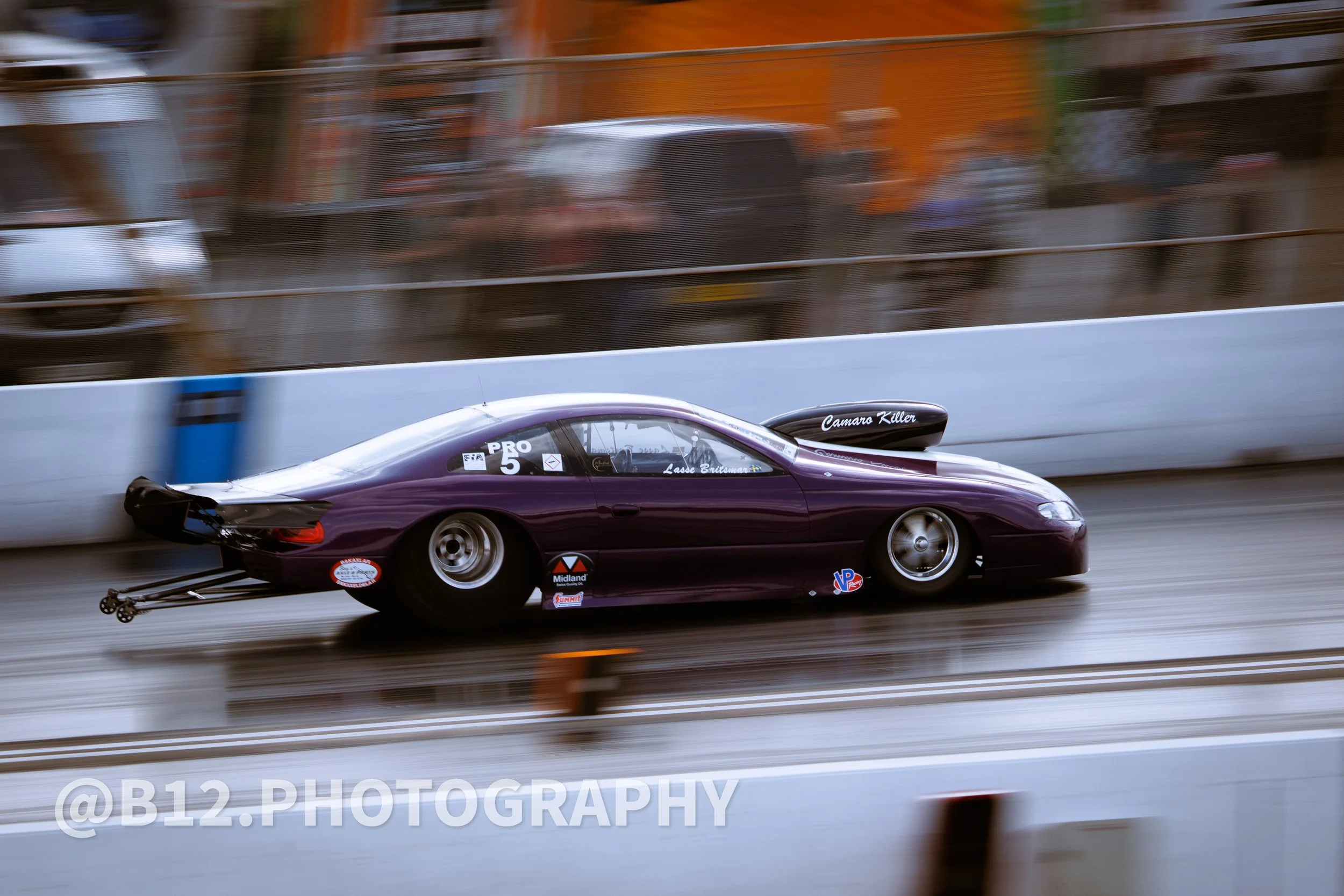 A purple race car moving quickly down a track, with motion blur in the background and on the wheels.