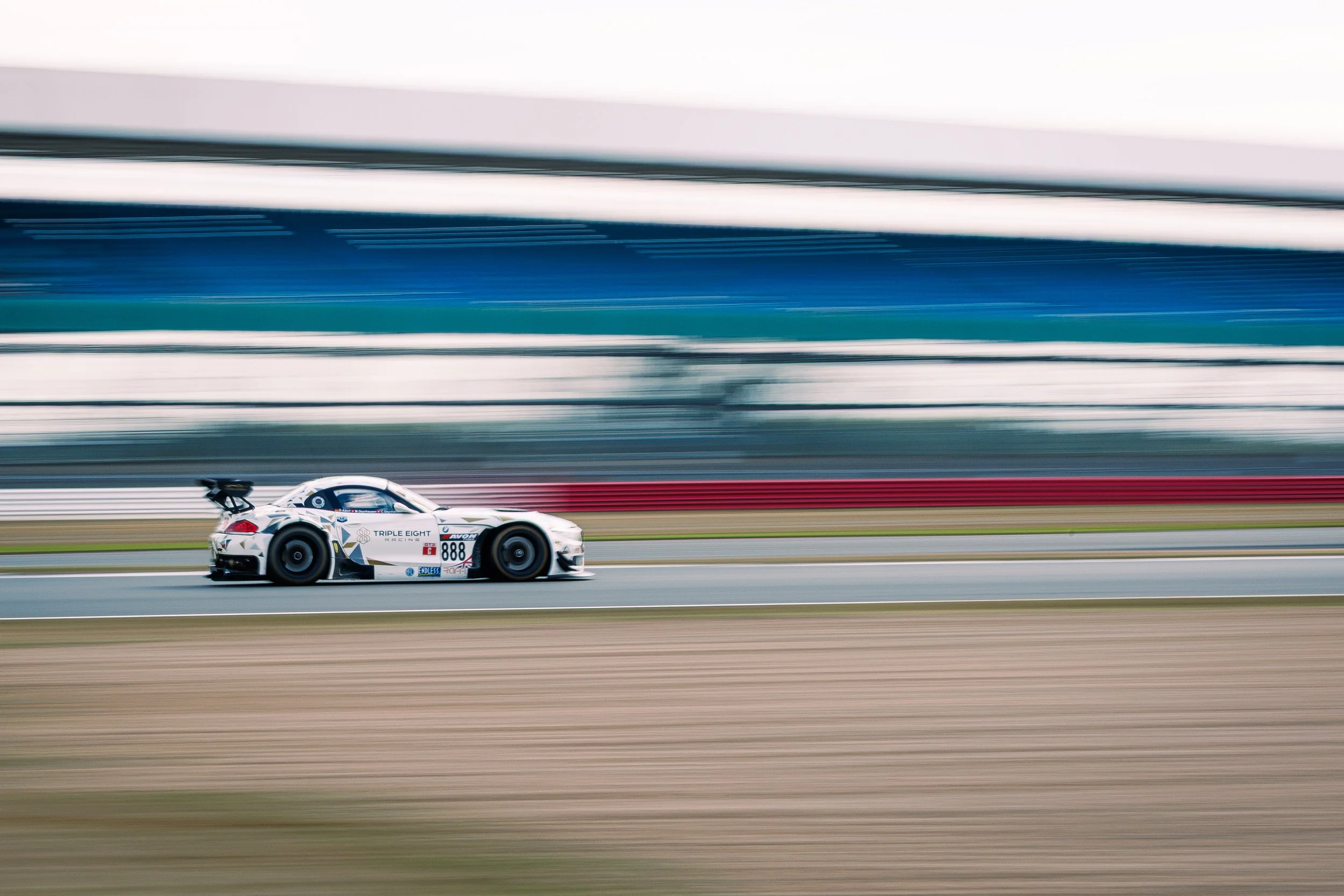 A racing car speeding on a race track with motion blur background.