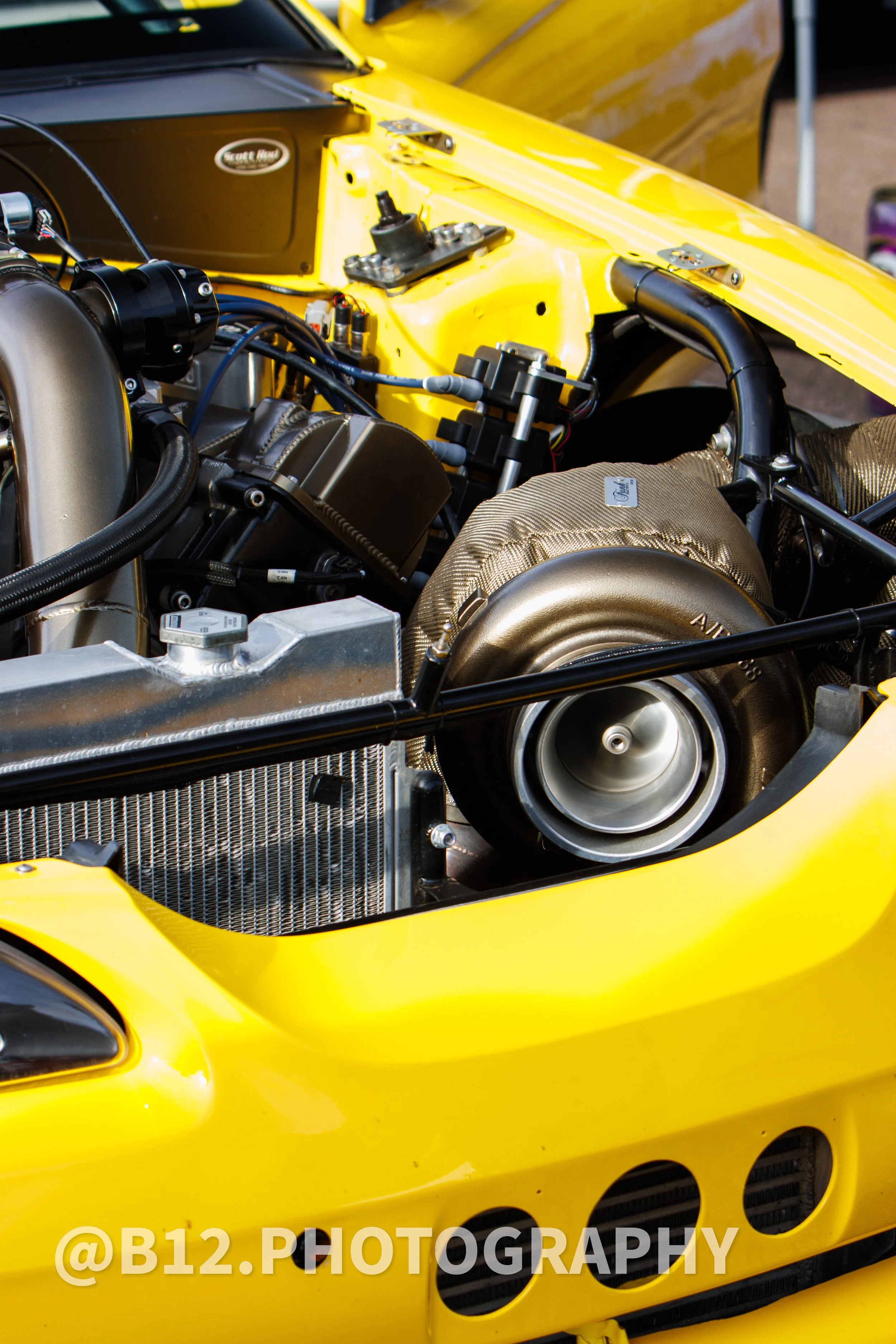 Close-up of a yellow race car engine with visible turbocharger.