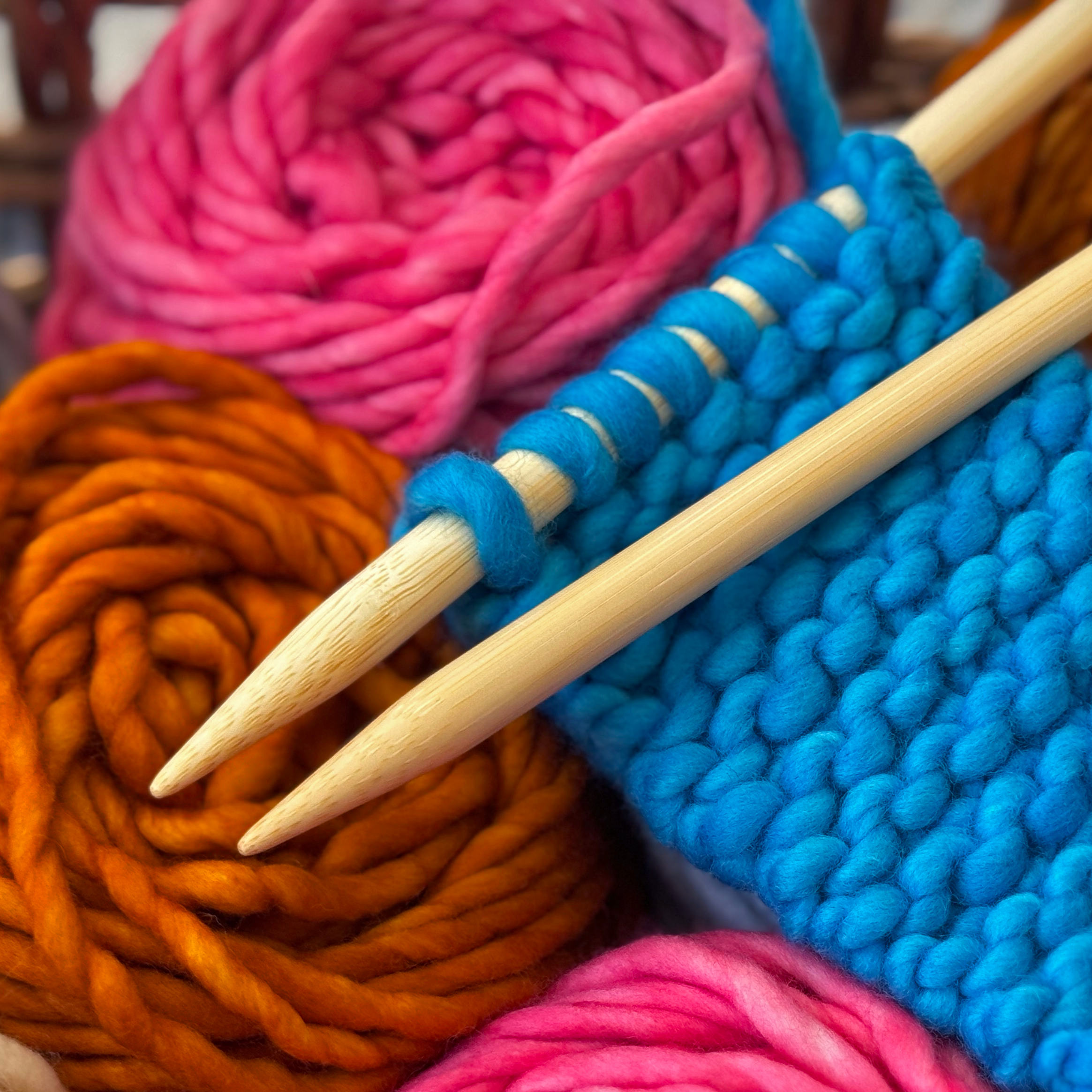Close-up of colorful yarn balls and knitting needles.