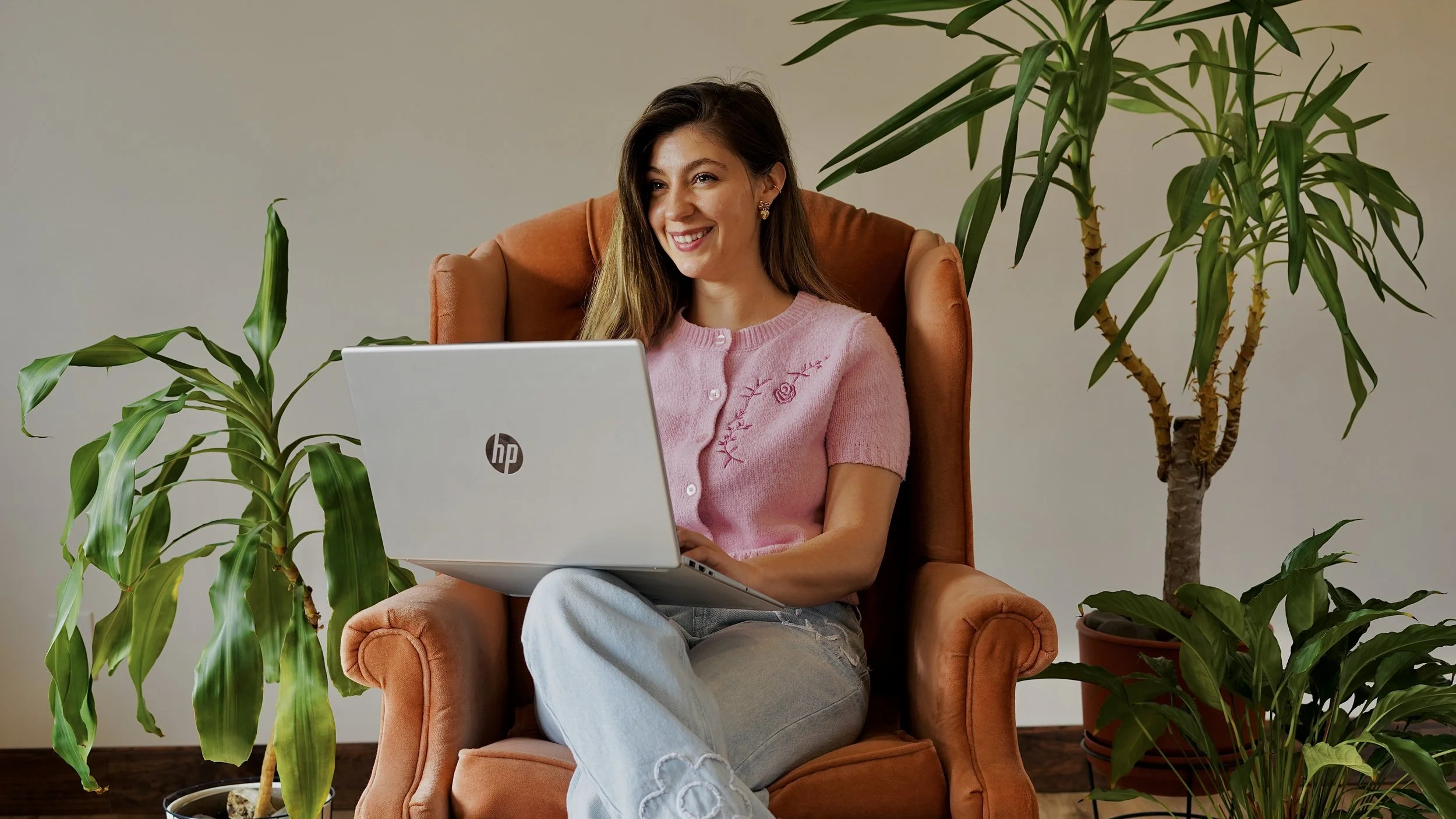 Mid Michigan social media, website, and branding specialist from Made Up Media sitting and working on her laptop.