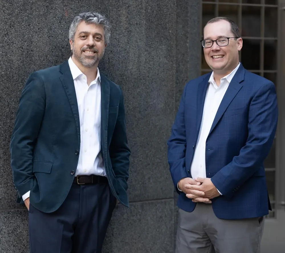 Steve Abreu and Peter Karol of Abreu Karol standing outdoors and smiling at the camera.