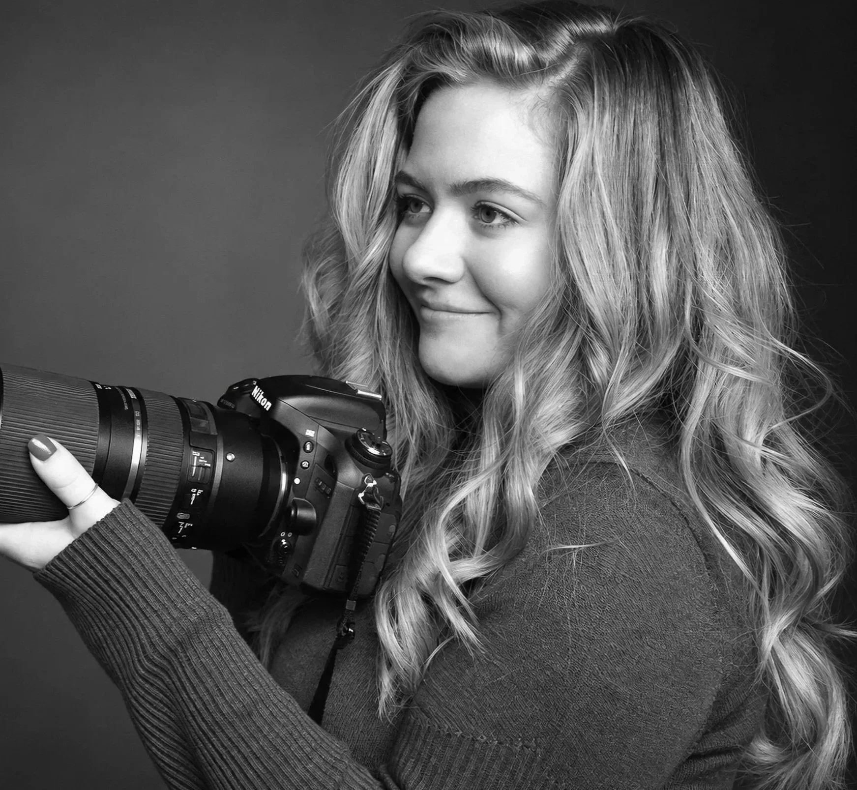 Black-and-white portrait of fine art nature photographer Iliana Romanul holding a camera.