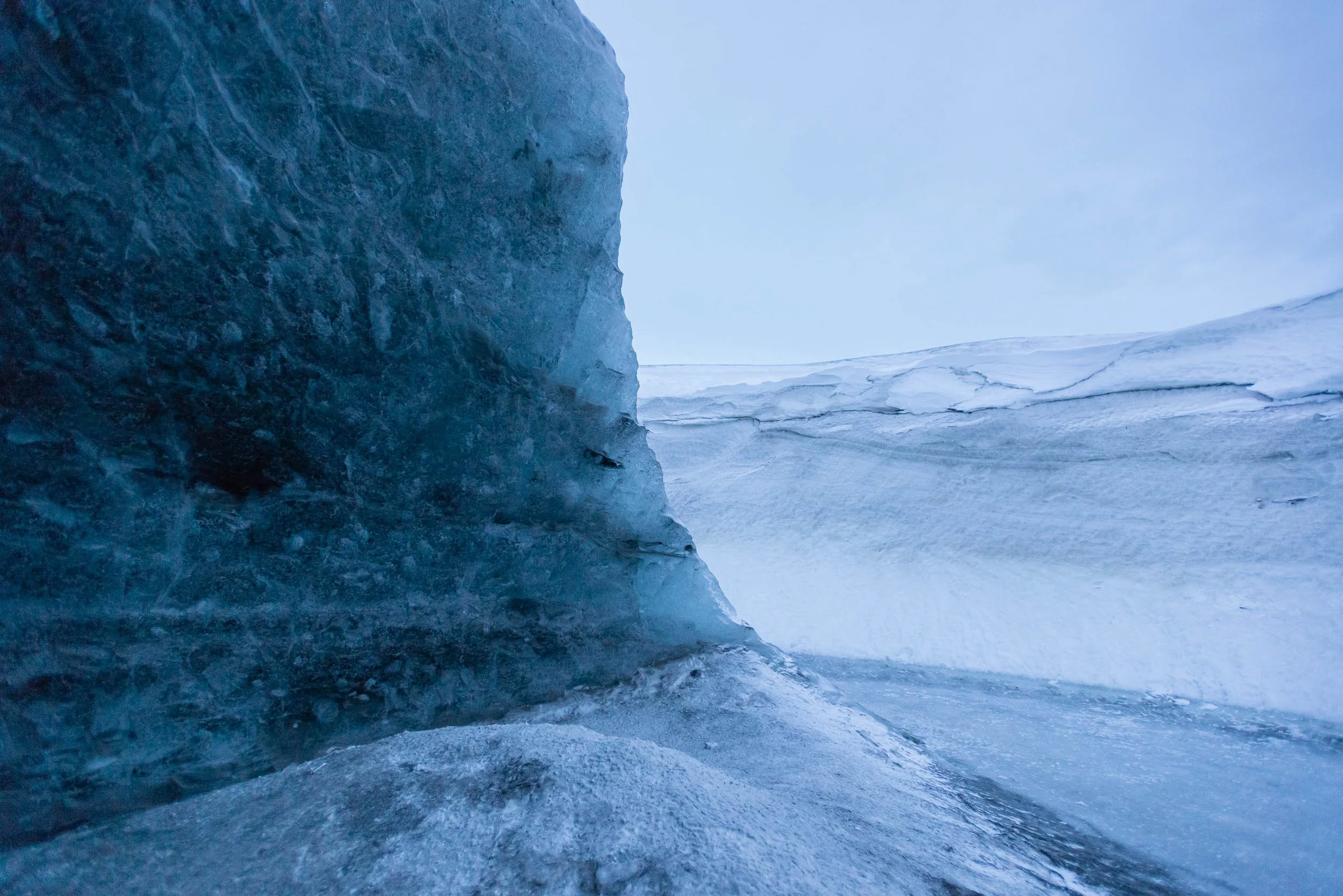 Blue ice wall and glacier field inside a Vatnajökull ice cave in Iceland.