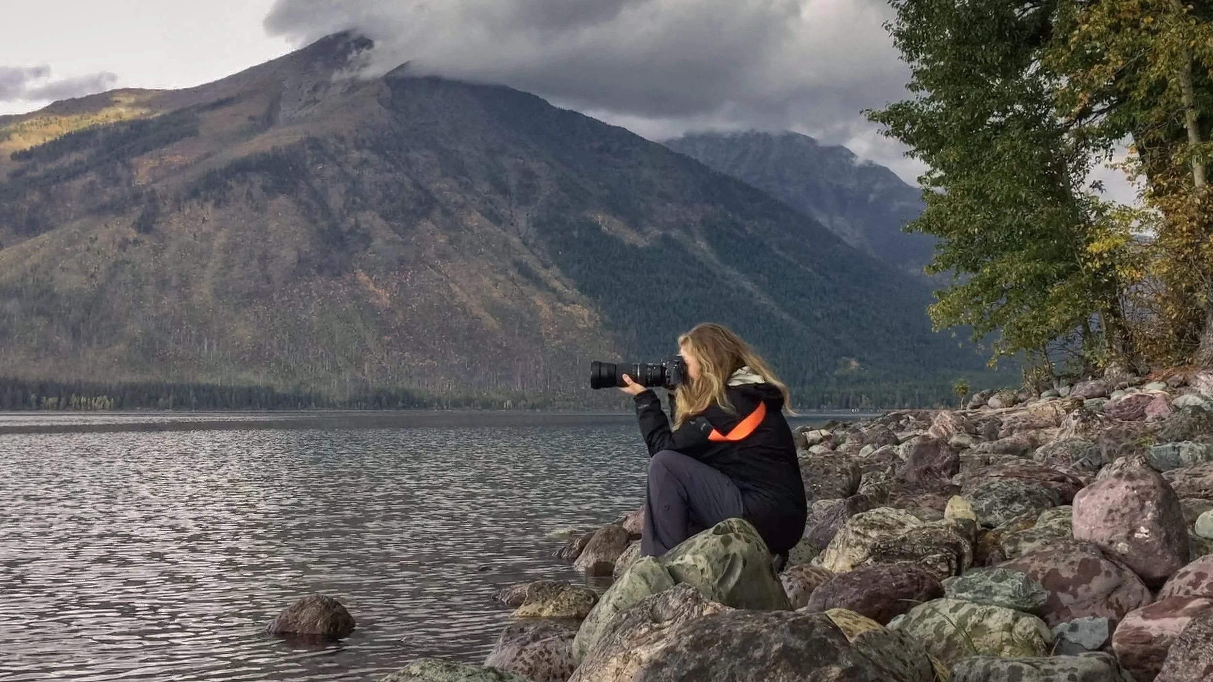 Iliana Romanul in the field with camera equipment, photographing a remote landscape.