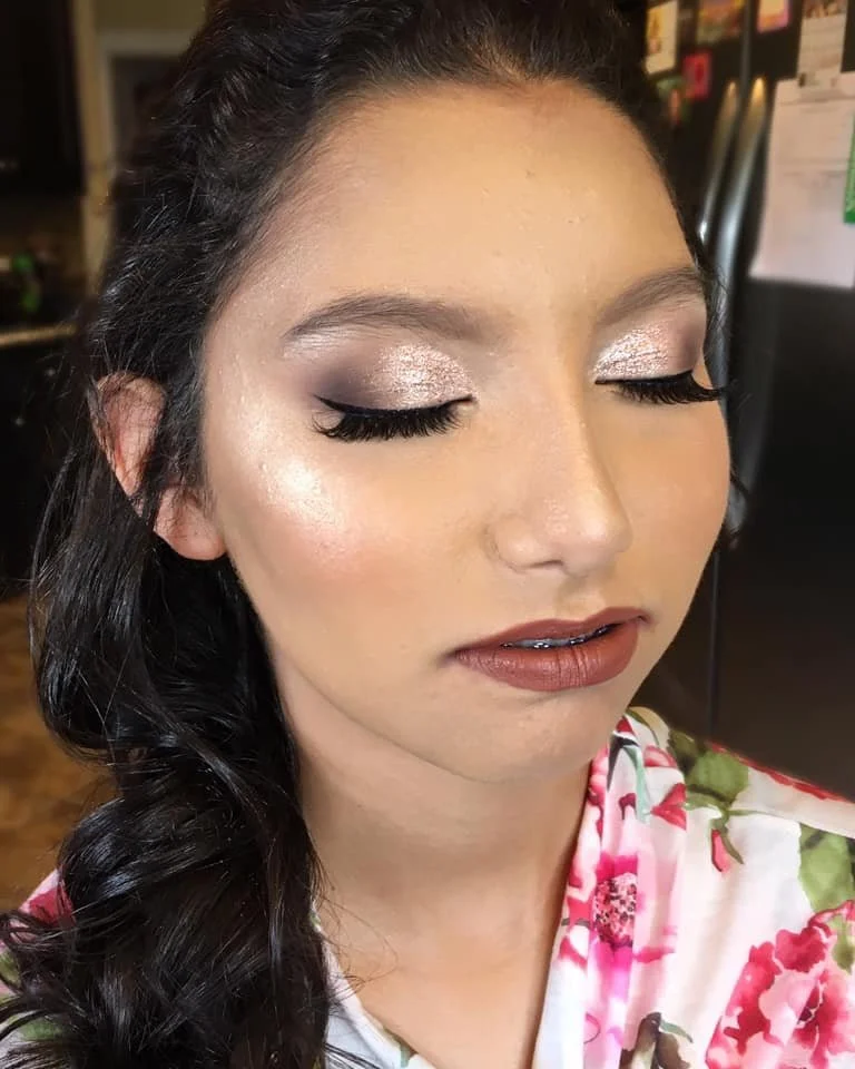 Woman with closed eyes showcasing shiny eye makeup, long eyelashes, and nude lipstick, wearing a floral robe.