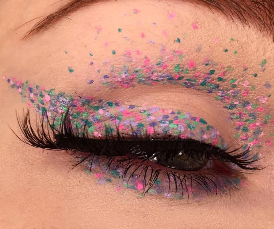 Close-up of a closed eye with colorful glitter on eyelids and around the eye.