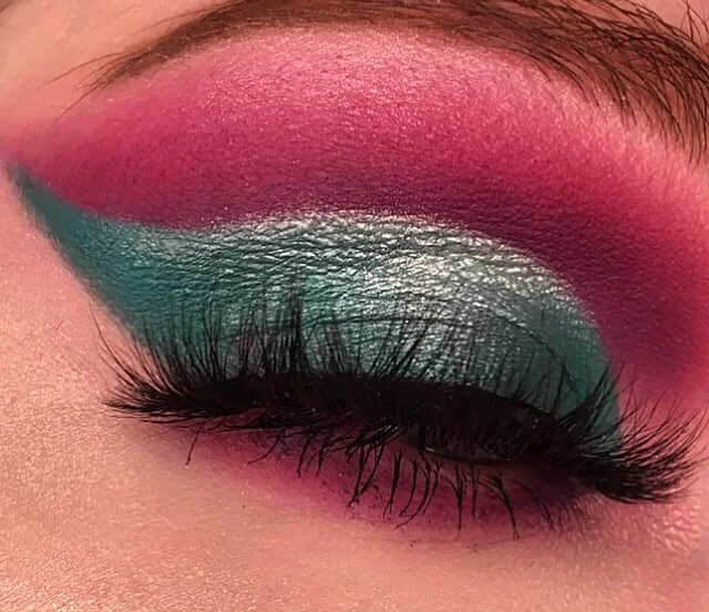 Close-up of a closed eye with vibrant pink and teal eyeshadow and long eyelashes.