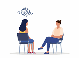 A woman and a counselor sitting in a therapy session, with the woman looking confused and the counselor listening attentively.