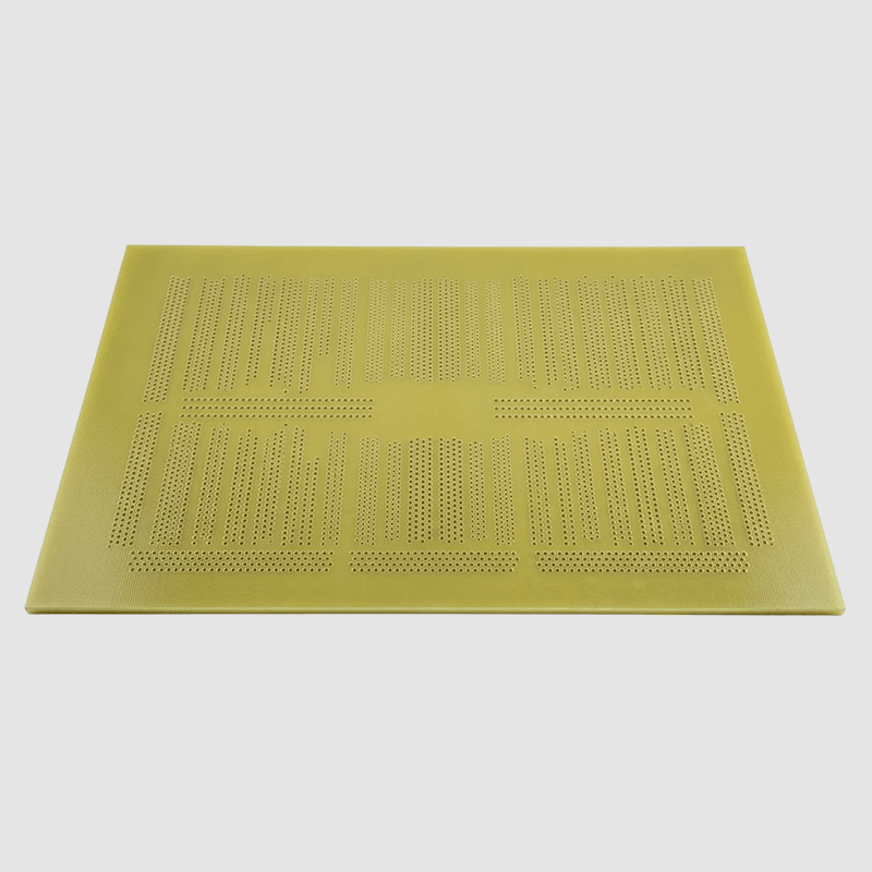 A yellow perforated work mat with various cutouts and patterns on a white background.