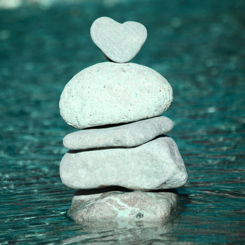 Stack of five stones with a heart-shaped stone on top, balanced on water.
