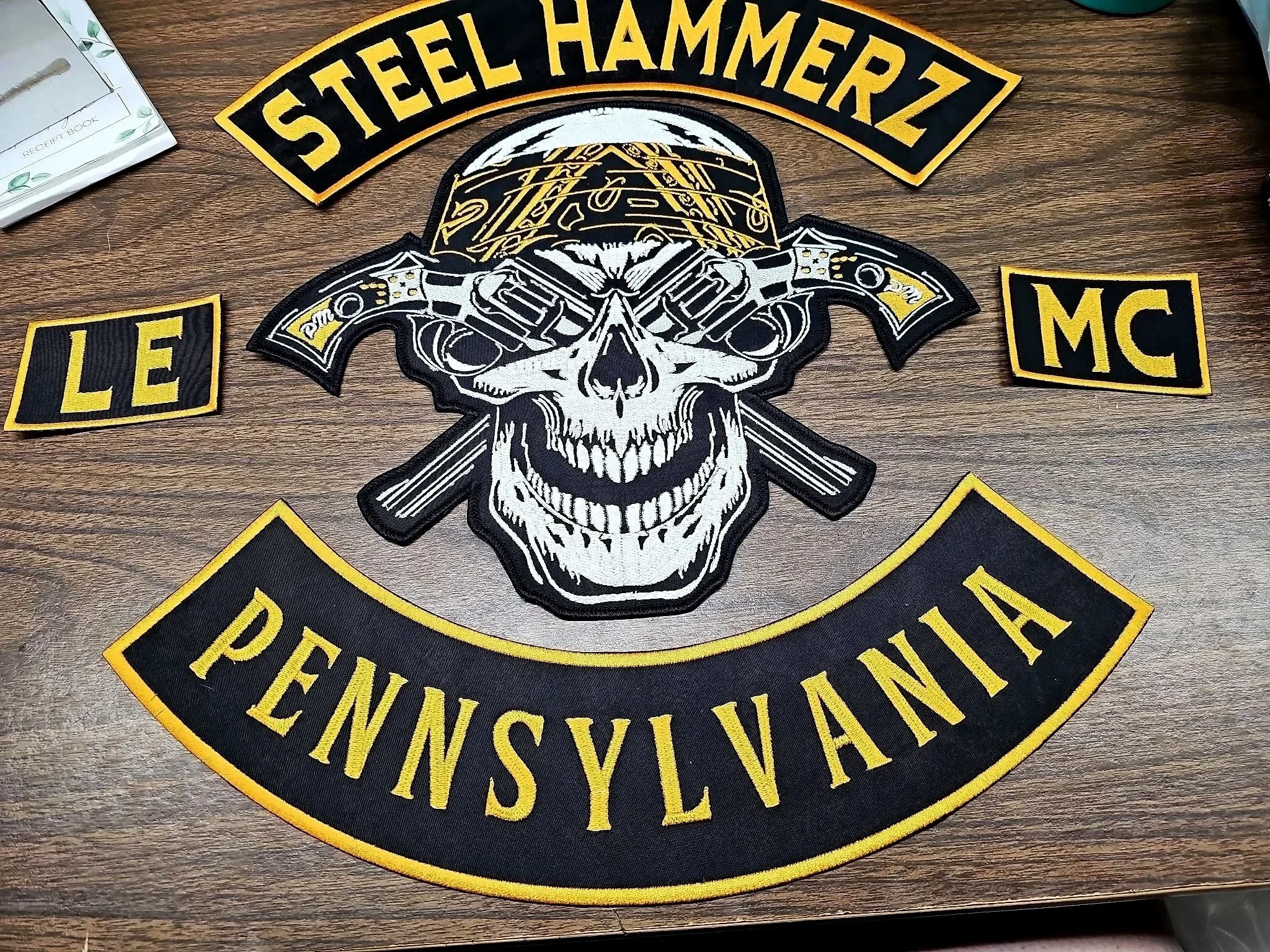 Patch with the logo of the Steel Hammerz Motorcycle Club, Pennsylvania, featuring a skull with a helmet, two revolvers crossed behind it, and the words 'Steel Hammerz' above and 'Pennsylvania' below.