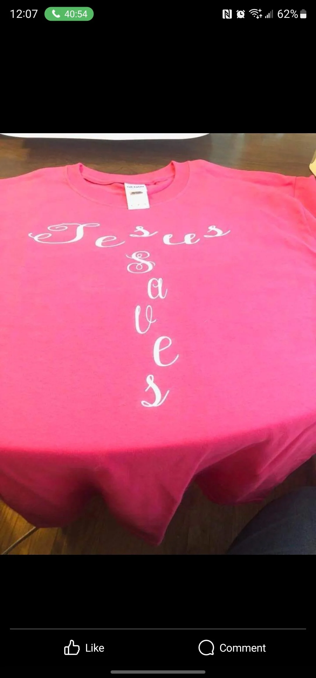 Pink T-shirt with the words "Jesus Loves" written in white cursive font, arranged vertically.