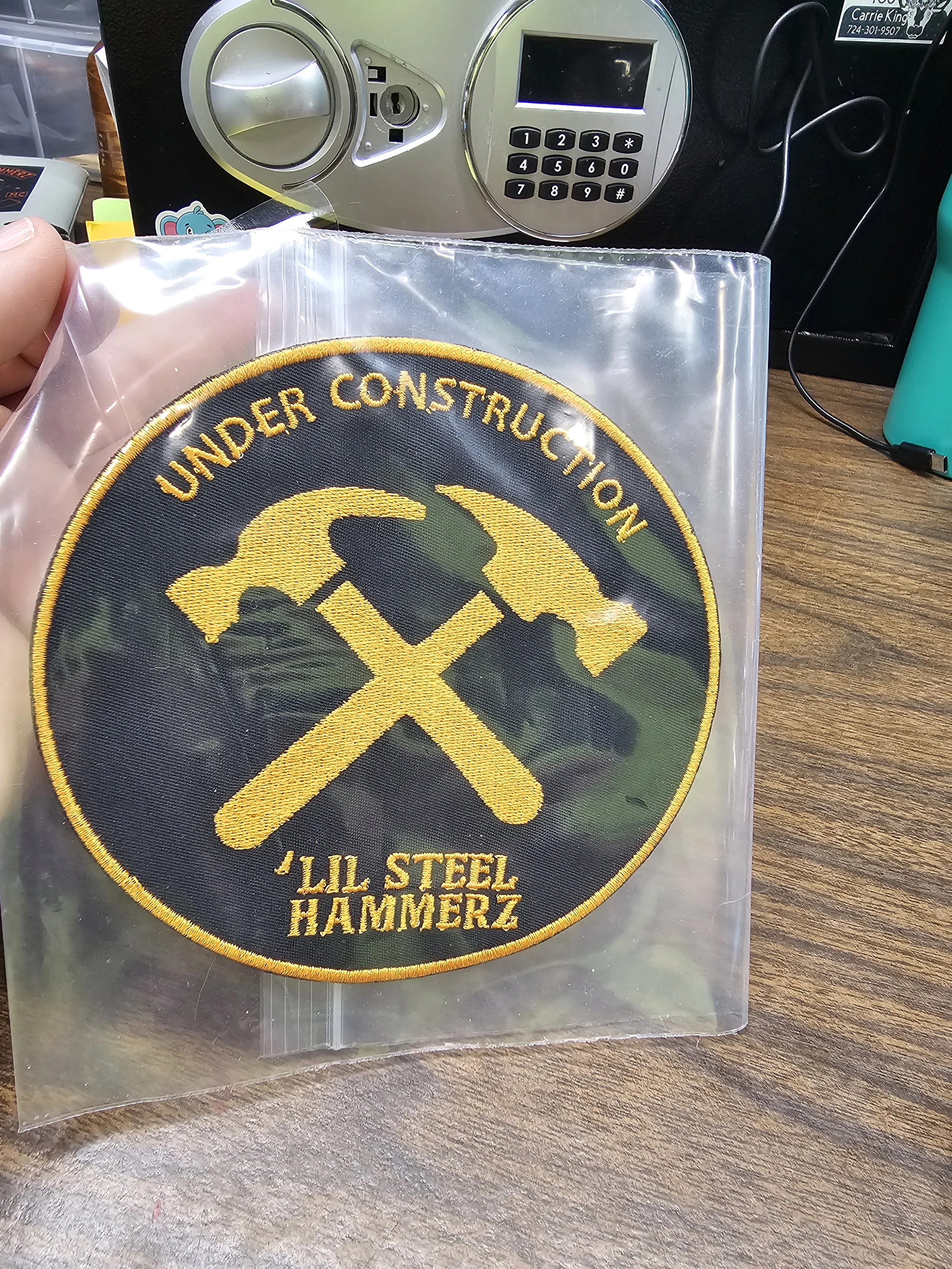 A round embroidered patch with a black background, yellow text and symbols, and a yellow border. The patch says 'Under Construction' at the top and 'Jill Steel Hammerz' at the bottom, with a yellow hammer and pick crossed in the center.