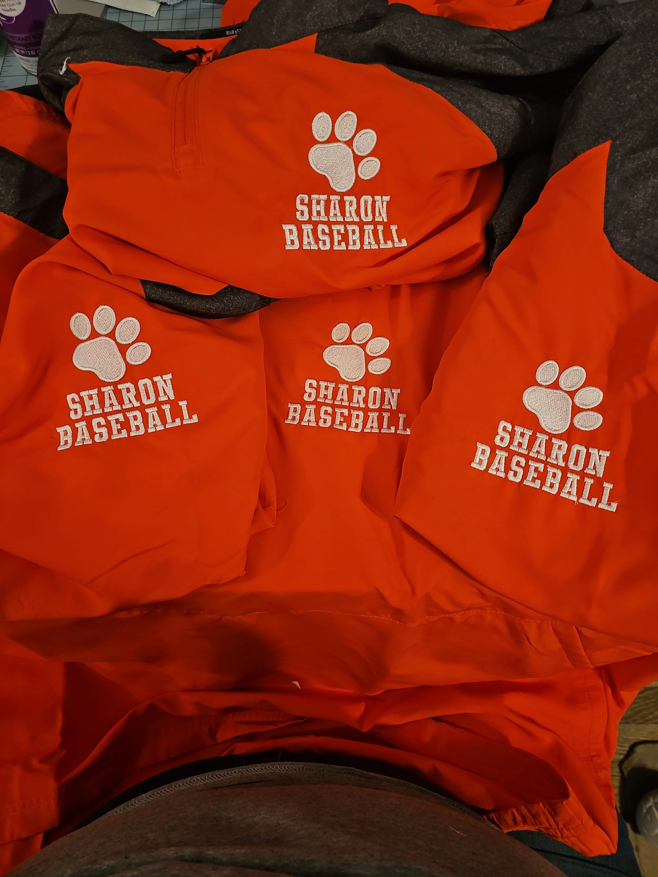 Orange sports drawstring bag displays white embroidered logo with a paw print and the text 'SHARON BASEBALL'.
