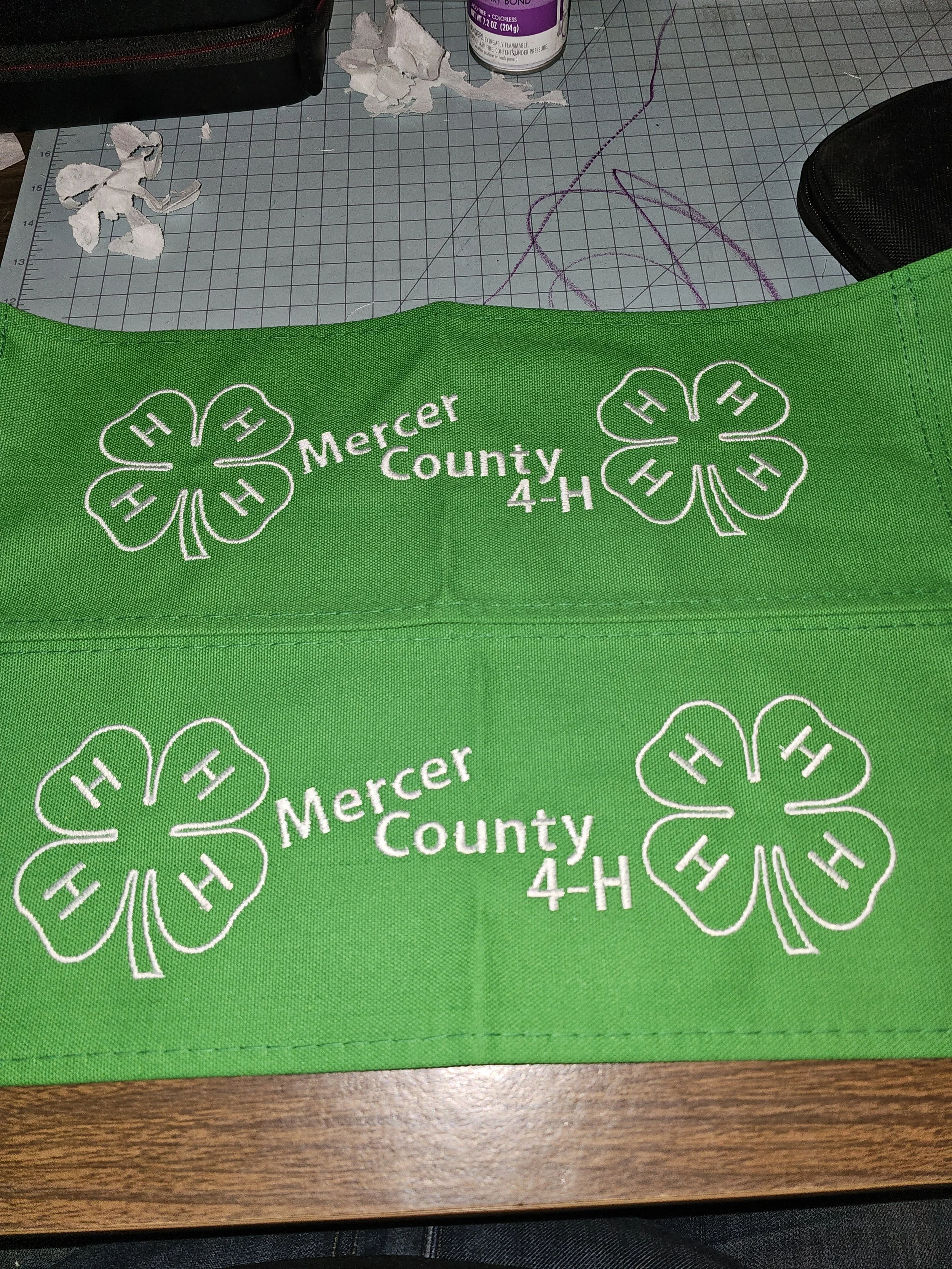 Green fabric with white embroidery of two four-leaf clovers and the words 'Mercer County 4-H'.
