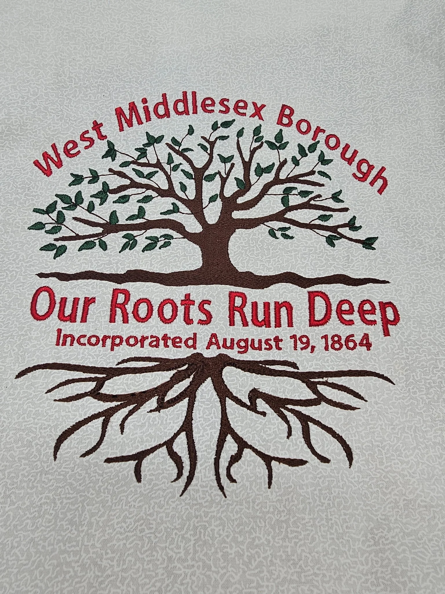 Embroidered logo of West Middlesex Borough featuring a tree with roots, with text 'West Middlesex Borough', 'Our Roots Run Deep', and 'Incorporated August 19, 1864'.