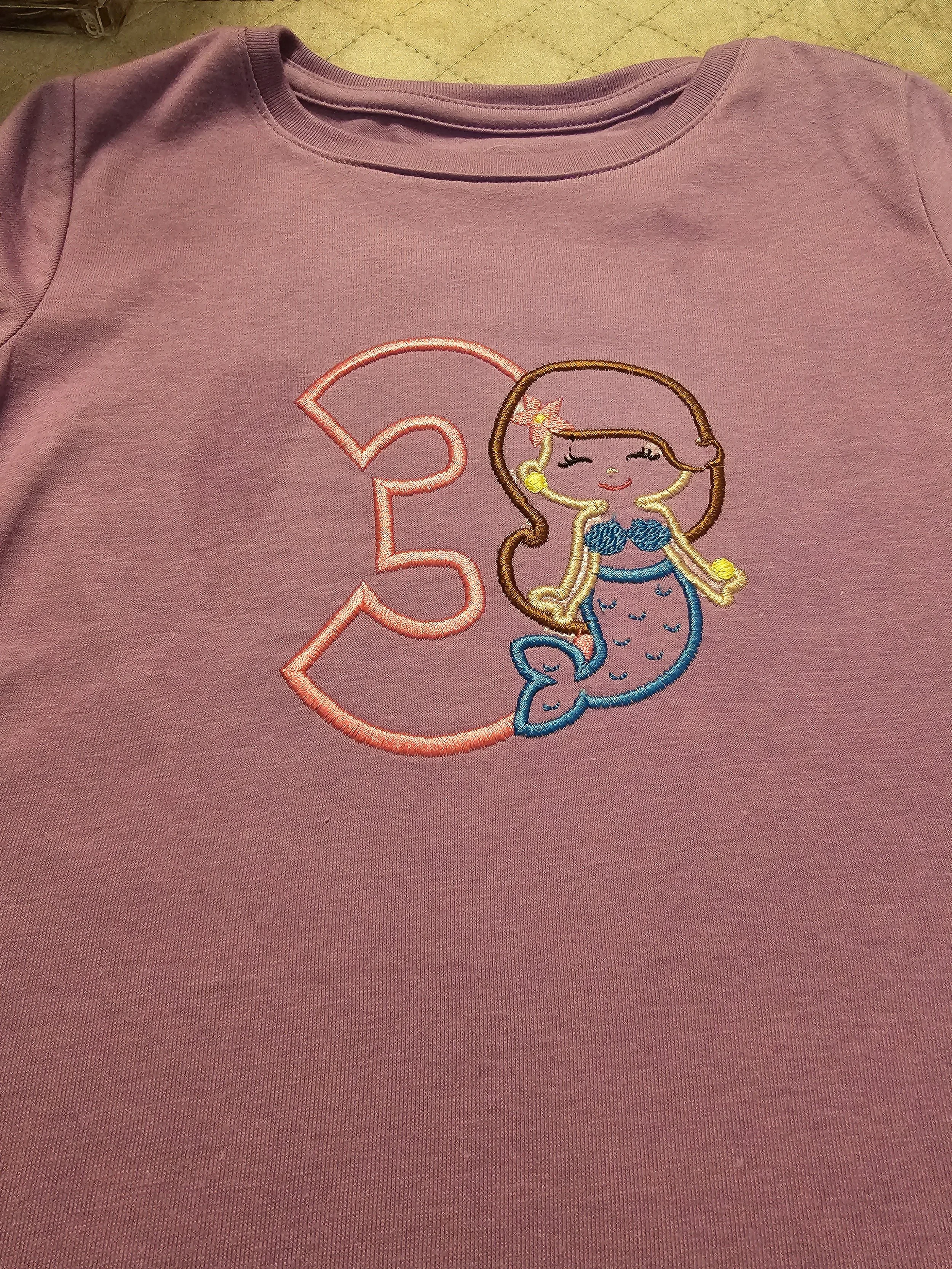 Pink sweatshirt with embroidered mermaid and the number 3.