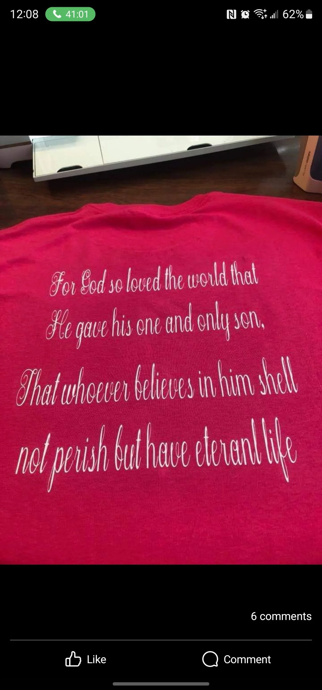 A pink shirt with religious text written in white cursive font that reads: "For God so loved the world that He gave his one and only son, That whoever believes in him shall not perish but have eternal life."