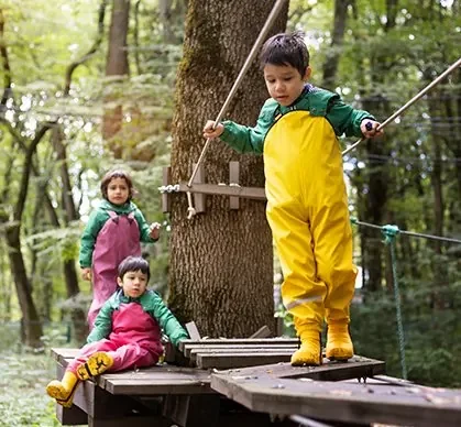 Children practicing balance and taking supported risks during outdoor forest school play.