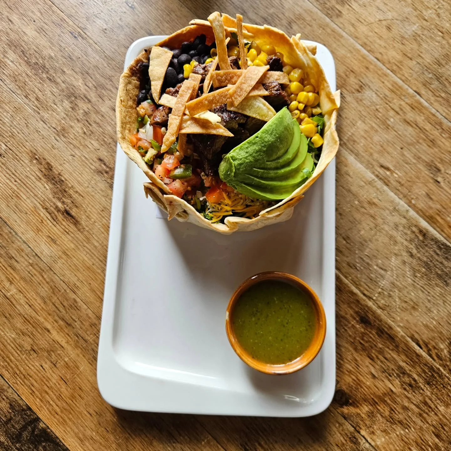 Looking for a meal that's both satisfying and fresh? Look no further than our delicious Ensalada Mexicana! We start with a crisp bed of green leaf lettuce & Mexican rice and top it with shredded cheese, pico de gallo, corn, black beans, in a flou