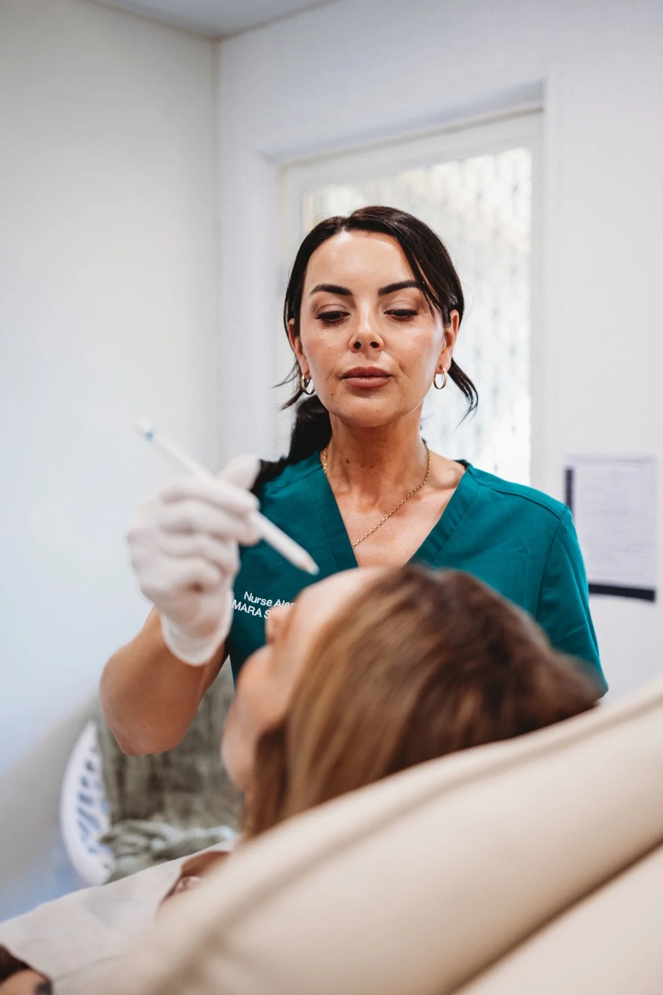 Nurse Alanna from Amara Skin Clinic using a white marking pencil to map a client's face before treatment