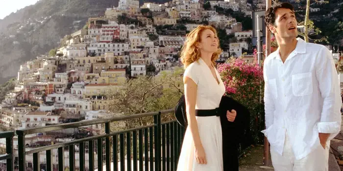 Scene from Under the Tuscan Sun A man and woman standing outdoors near a railing with a hillside of houses in the background.