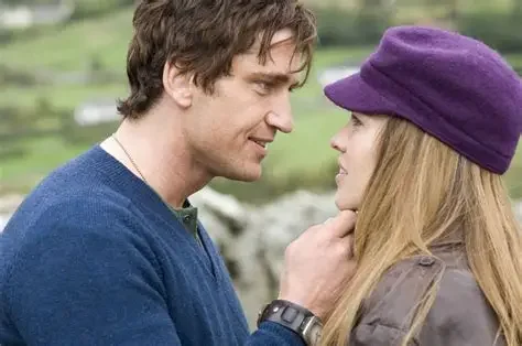 A Scene from the movie P.S I love you, facing each other closely, with the man's hand gently touching the woman's chin.