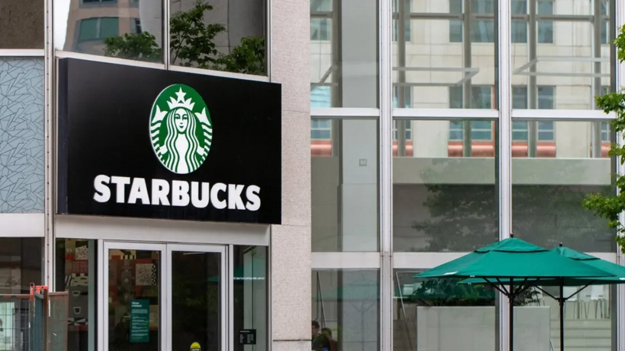 Starbucks storefront with green parasol outside, modern glass building reflections. HVAC Services New York City, USA.