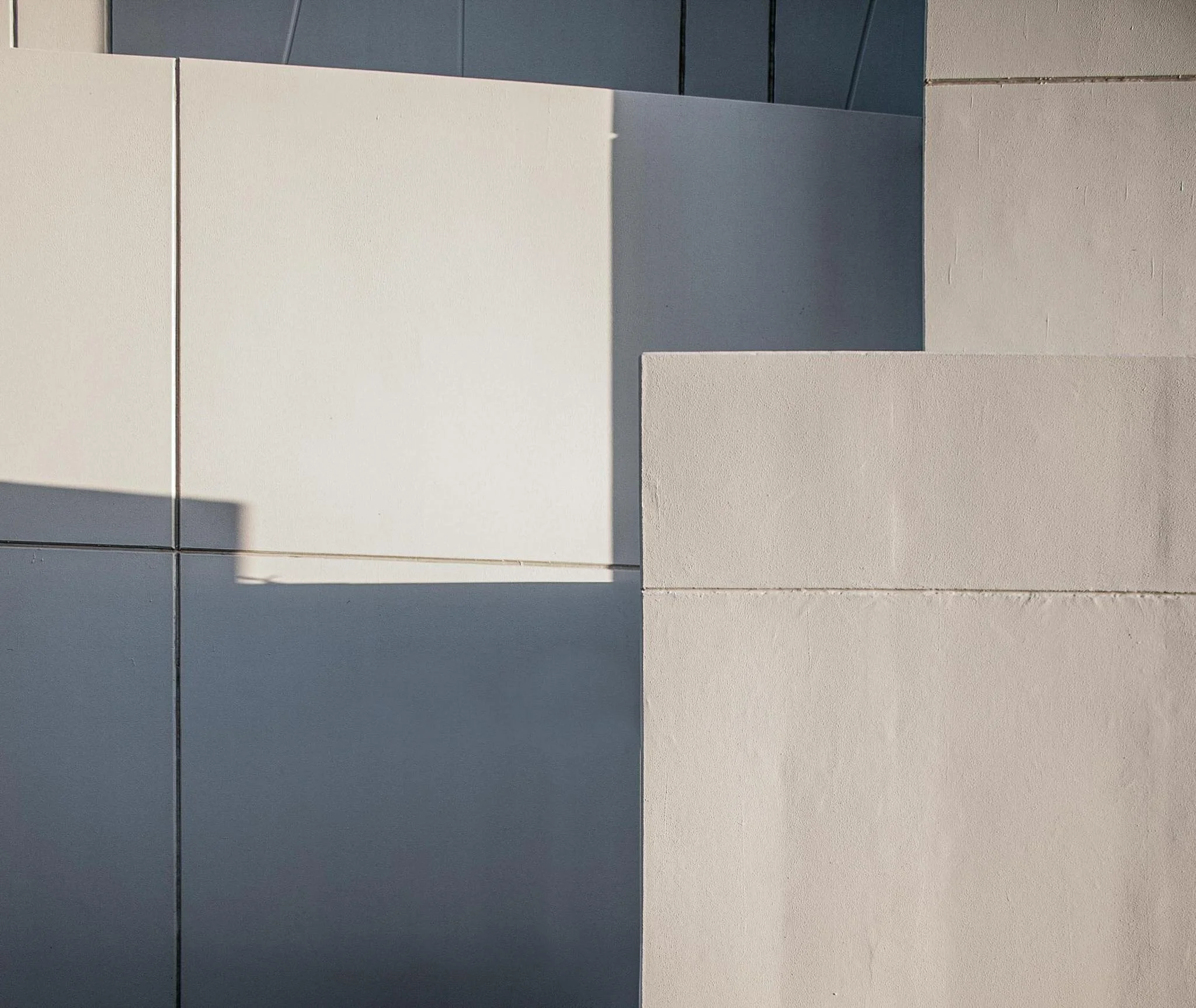 A person writing on a white sheet of paper with a black pen, surrounded by notebooks, a smartphone, and other office supplies.