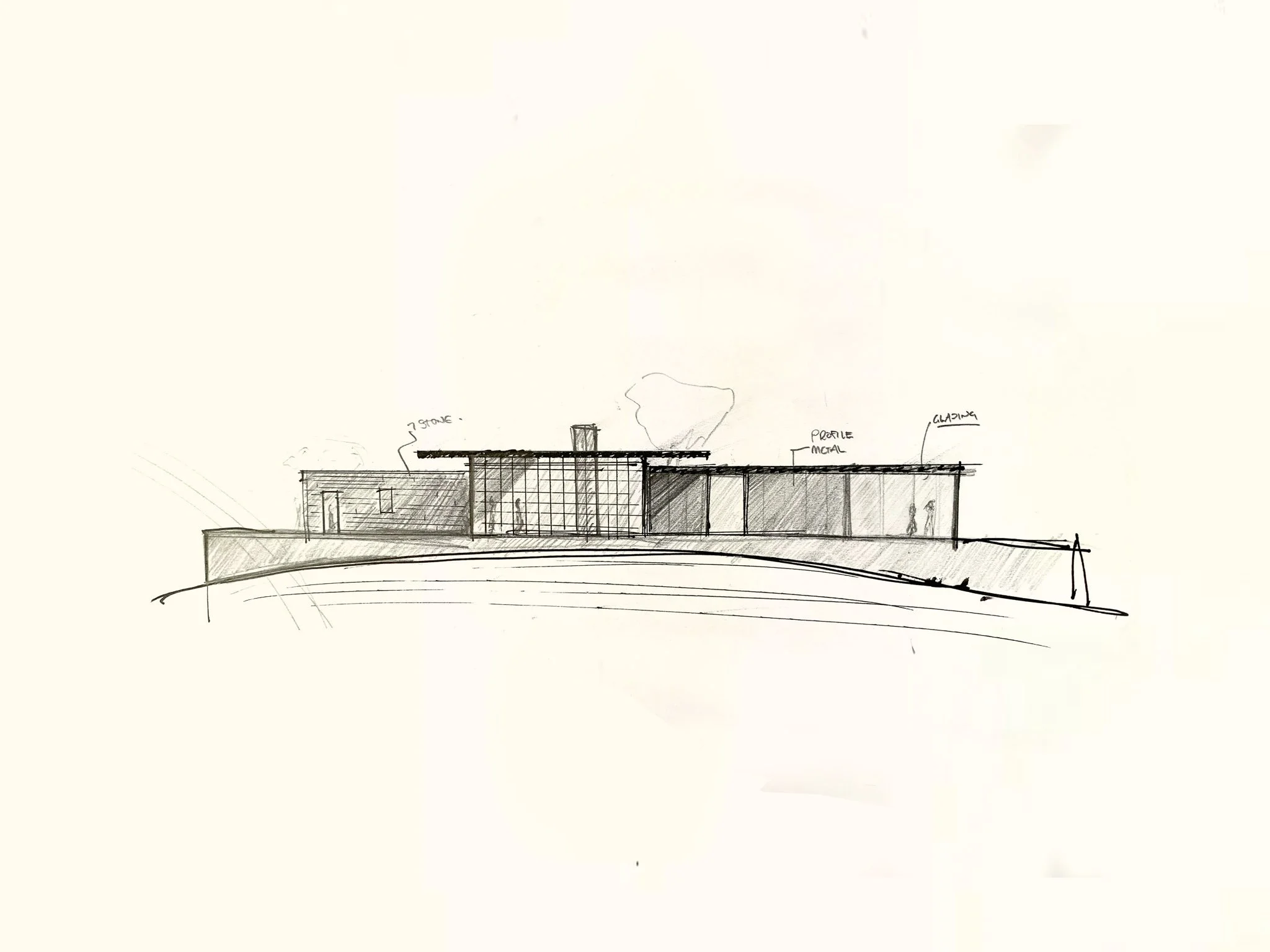 Person writing with a black marker on a white piece of paper, with a partially visible photo or postcard, and green plant leaves in the background.