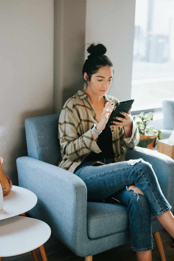 Woman sitting in chair wearing relaxed clothes reading ipad mini.