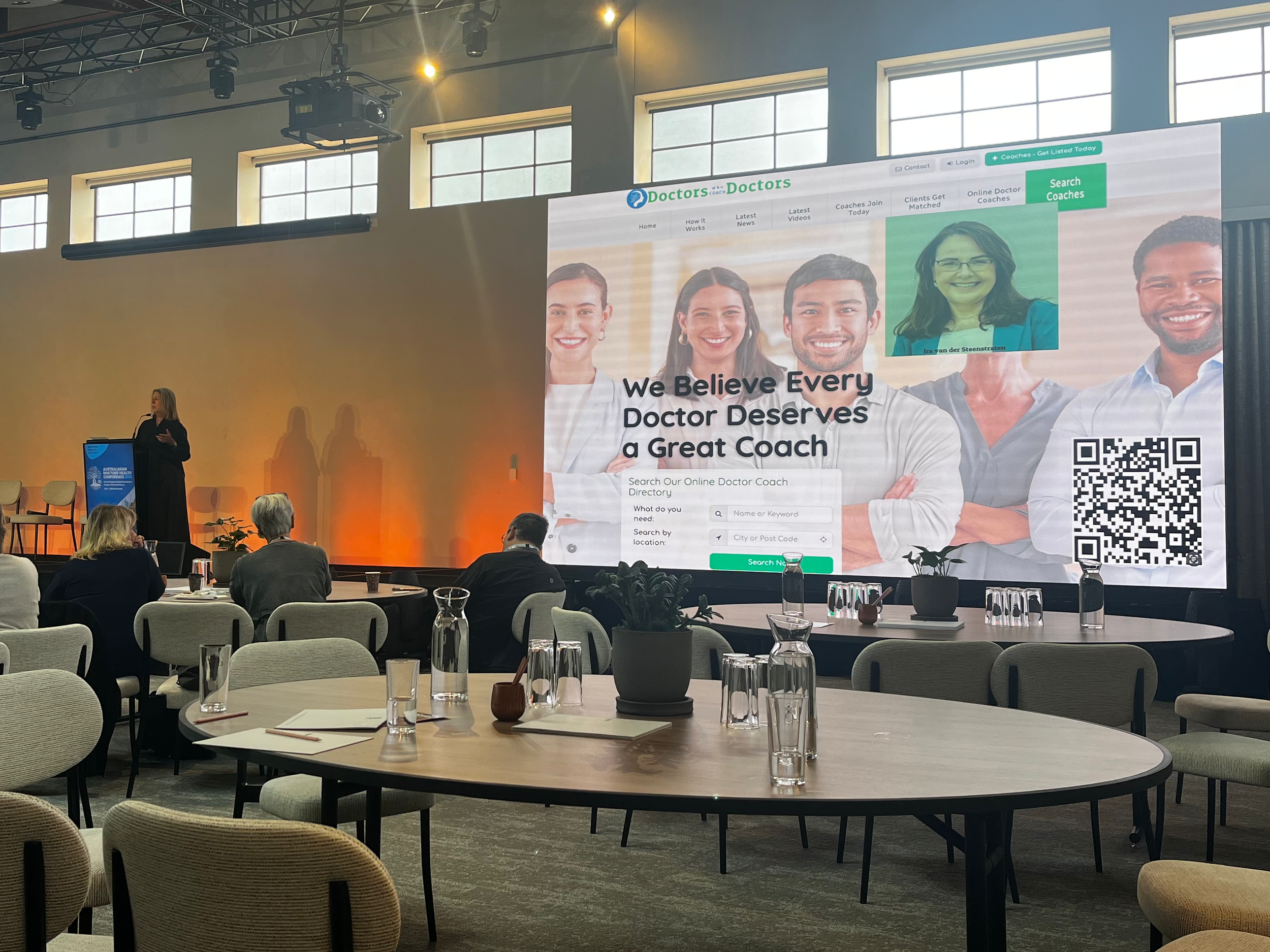 Photo of Dr Tabitha Healey presenting with a slide “We believe every doctor deserves a great coach