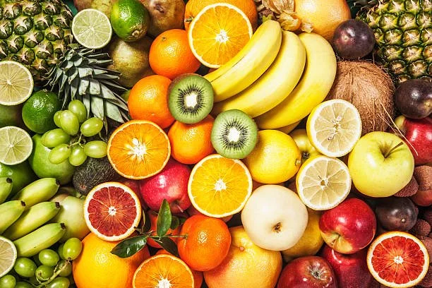 A colorful assortment of fresh fruits including oranges, bananas, apples, grapes, pineapples, kiwis, and lemons.