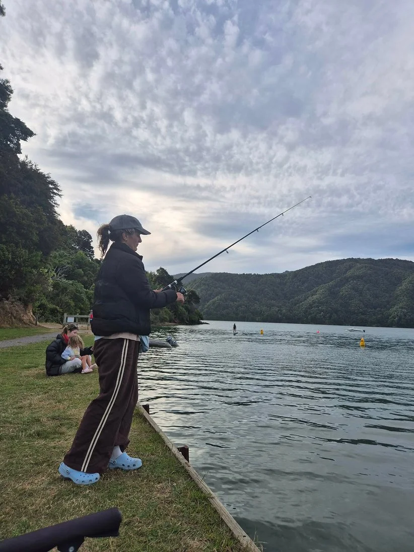 Artist Anita Robinson fishing at Momorangi Bay, New Zealand, taking a creative pause before returning to the abstract painting studio.