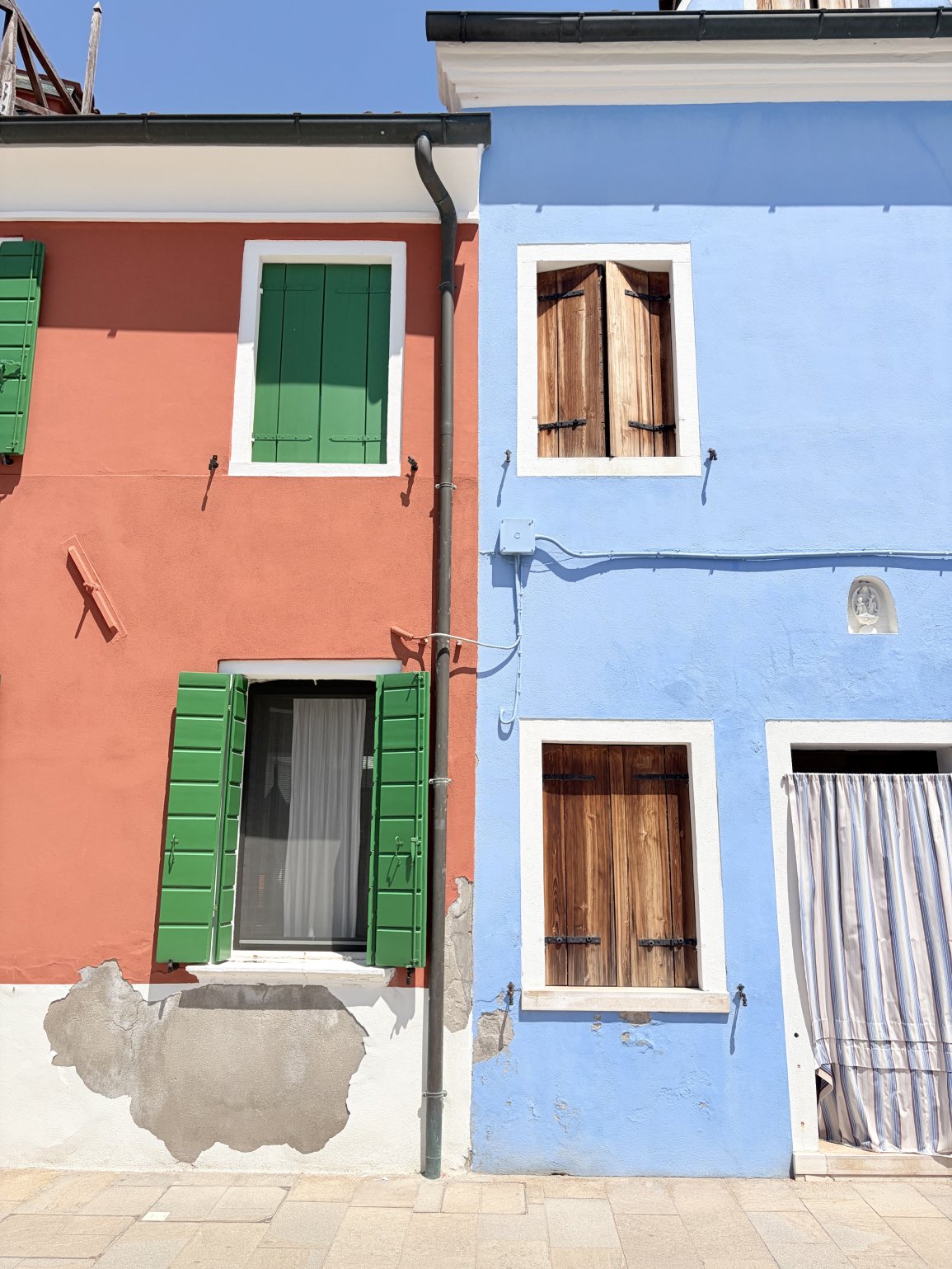 Peach and blue houses with green shutters in Burano, Italy