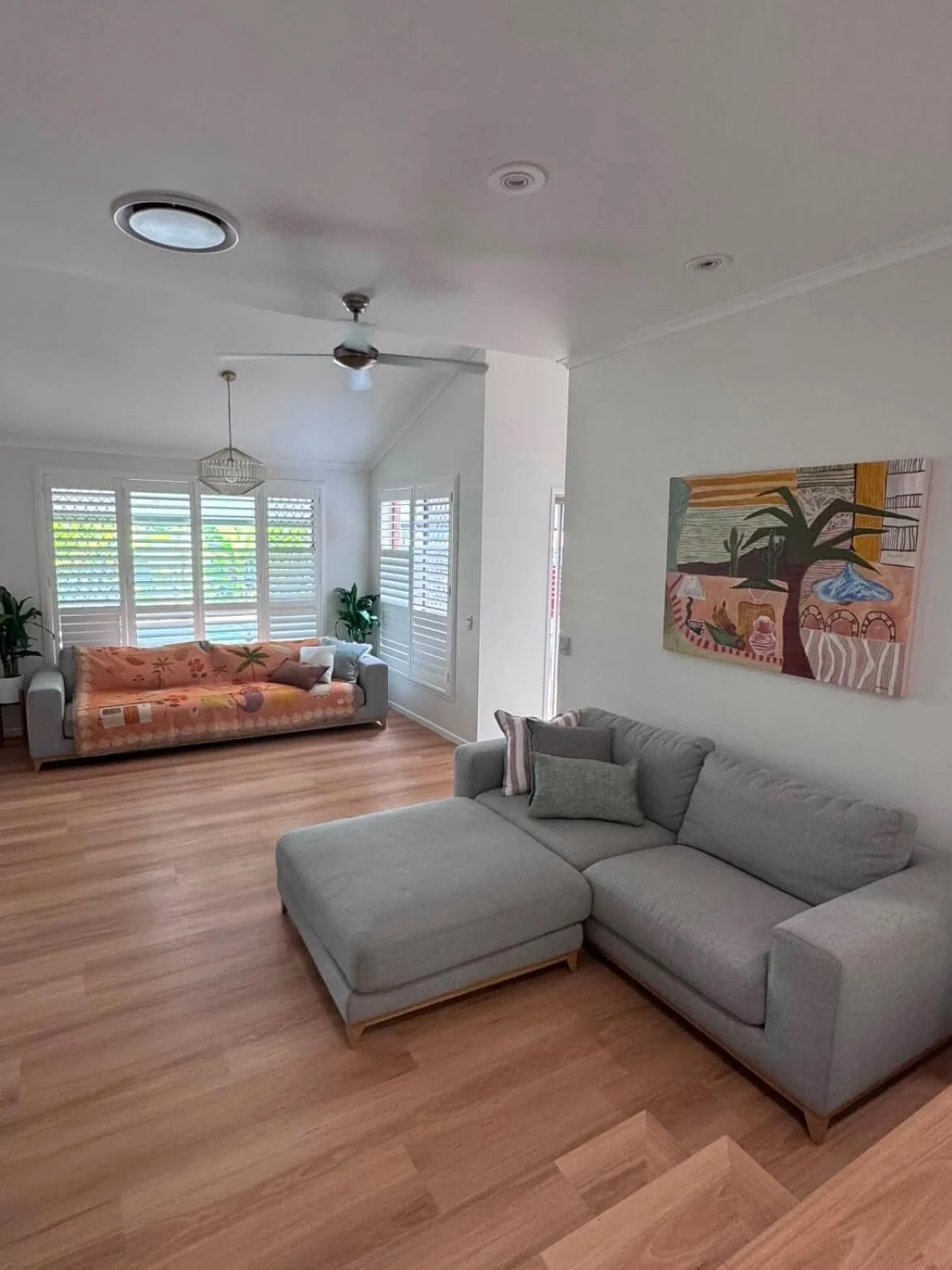 Under the Palm original painting by Anita Robinson hanging above a grey sofa in its collector’s home.