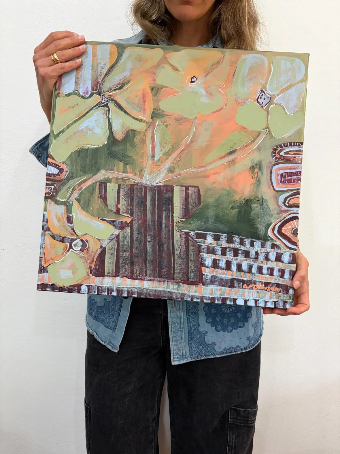 Abstract mixed-media painting titled 'Meet The Sunday Vase' featuring an earthy color palette of olive green, warm terracotta, soft peach, and blue accents, held by the artist.