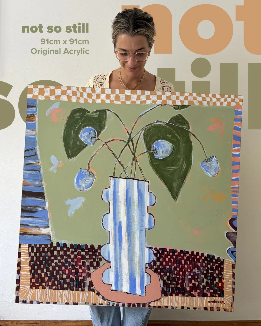 Artist Anita Robinson holding Not So Still, a large 91x91cm original green abstract painting with a striped vase.
