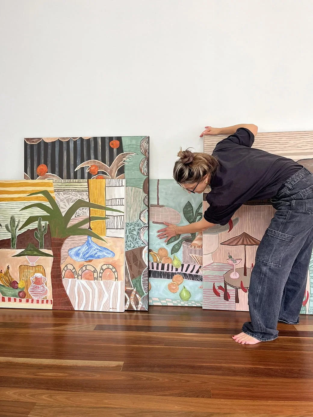 Abstract artist Anita Robinson in her Sydney studio arranging large-scale acrylic and mixed-media paintings on timber floors.