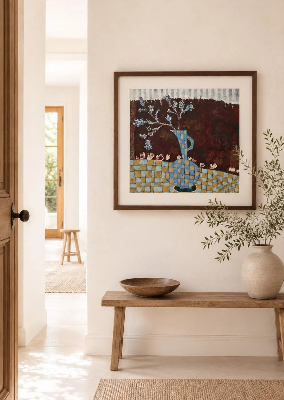 Framed abstract art print titled After the Picnic hanging in a bright, modern earthy entryway above a rustic timber bench with a ceramic vase and wooden bowl.